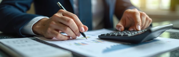 Business professional reviewing financial charts and using a calculator to analyze tax impacts and savings opportunities under the One Big Beautiful Bill (OBBBA) for small- to medium-sized businesses | vcfo